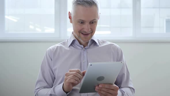 Middle Aged Man Excited for Success While Using Tablet