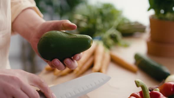 Close up of hands of woman preparing avocado at the kitchen