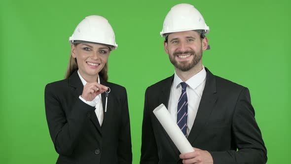 Male and Female Engineer Holding Key and Documents Against Chroma Key