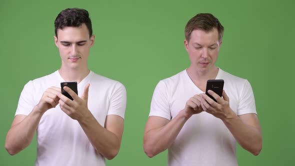 Two Happy Young Handsome Men Using Phones Together