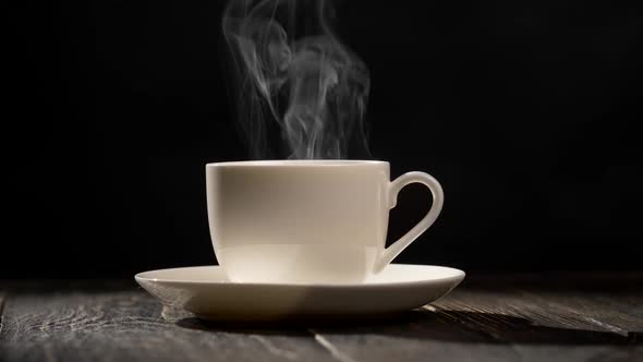 Cup of Hot Coffee. Steam Coming Out of a Coffee Cup Standing on a White Saucer on a Wooden Table