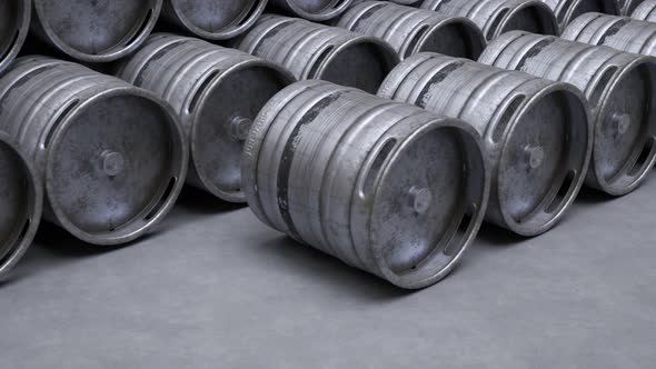 Multiple metal beer kegs being rolled on the ground in endless, seamless loop.