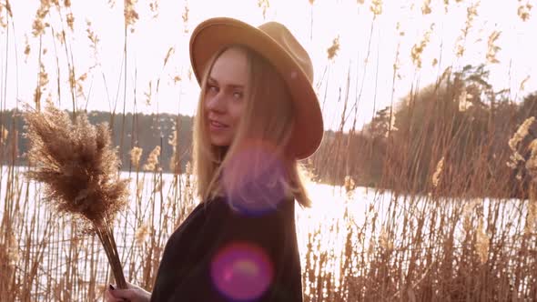 Millennial Woman European Blonde Woman Smiling with Beige Hat in Black Sweater in the Countryside