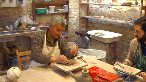 Potter teaching his colleague to mold the clay