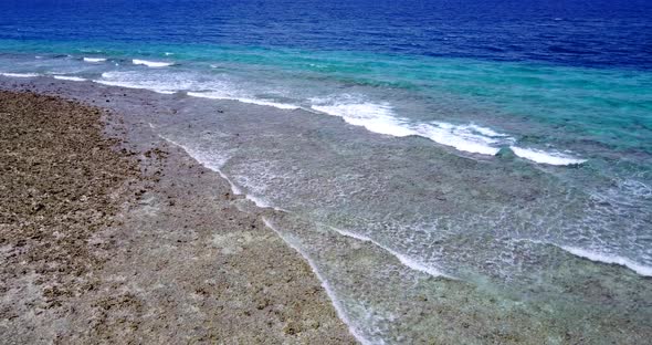 Daytime flying clean view of a paradise sunny white sand beach and blue sea background 