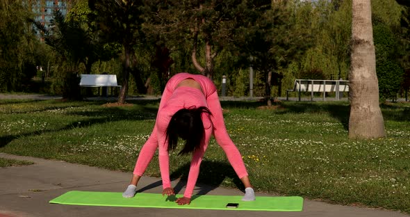 Young attractive multi ethnical woman wearing pink sportswear, pants and top, doing stretching yoga