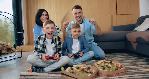 Parents Encouraging their Two Sons which Playing Video Game