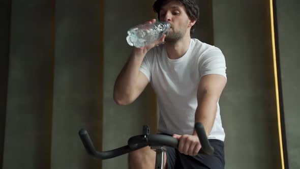 Young Man Drinks Water in the Gym