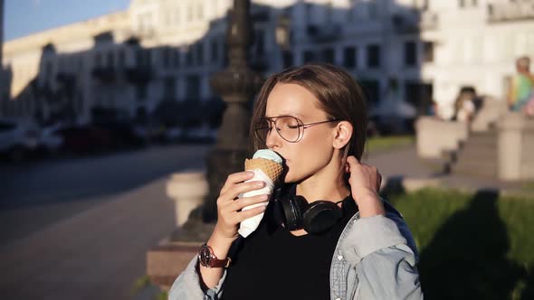 Young Woman in Orange Shirt Enjoying Soft Vanilla Ice Cream in Waffle Cone Outdoors in Slow Motion