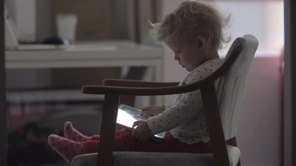 Toddler girl watching cartoons on tablet computer at home