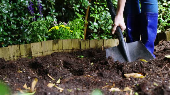 Person mixing soil with shovel in garden