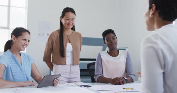 Biracial businesswoman shaking hands of smiling diverse female business colleagues in office