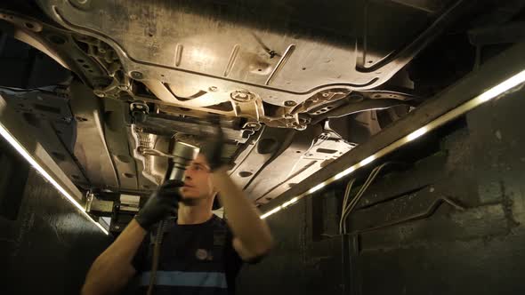 Auto mechanic working underneath car lifting machine at the garage. Auto repair 