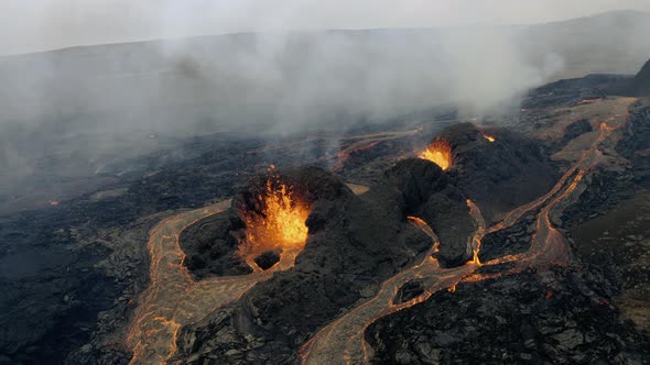 Aerial view around lava bursting out through volcanic fissures and holes in the earth- orbit, drone