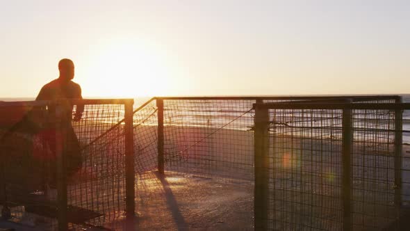 Focused african american man running up stairs, exercising outdoors by seaside at sunset