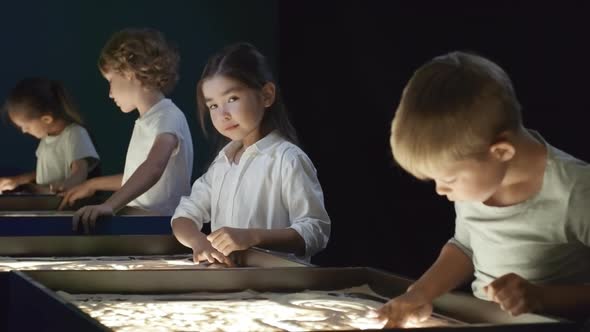 Adorable Asian Girl Smiling in Sand Animation Class