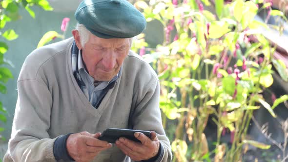 The Old Grandfather Uses a Smartphone Looks Closely