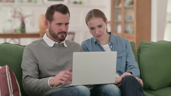 Couple Reacting To Loss on Laptop While Sitting on Sofa