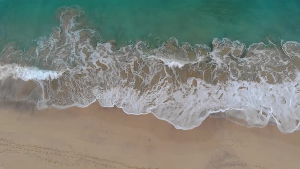 Ocean waves crashing on Matadouro beach. Aerial top down sideways