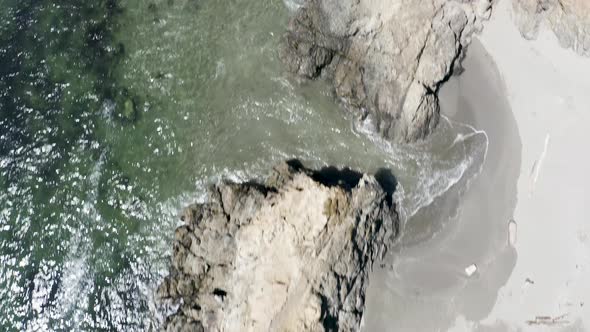 Aerial top-down view of crashing waves on a rocky beach