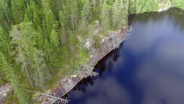 Drone orbits on beautiful scenery in the boreal wilderness. Calm, mirror surface lake with sky refle