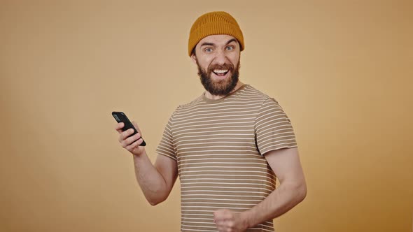 Mature Man Looks at Phone with Shocked Expression and Smiles