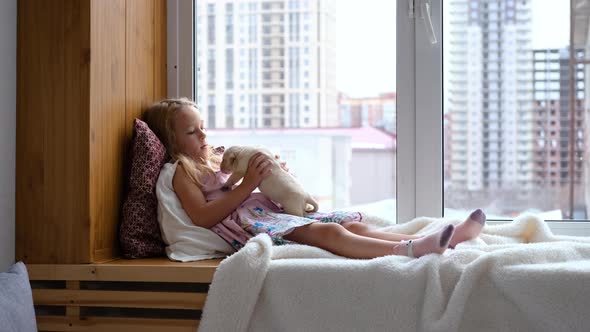 Child Girl Petting Labrador Puppy on Windowsill