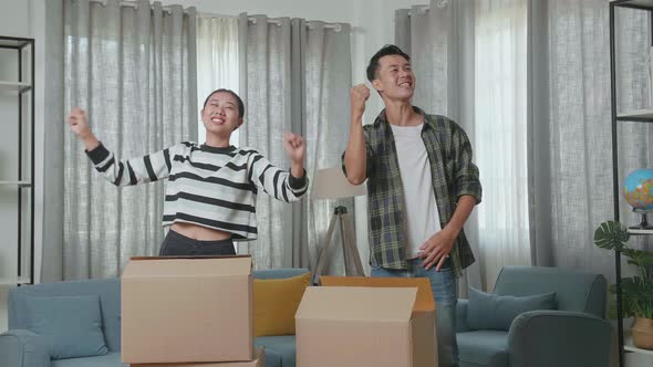 Happy Young Asian Couple Celebrating Finish Carrying Cardboard Boxes With Stuff Into A New House