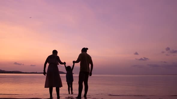 Family of Three Playing on the Tropical Beach at the Sunset Time. Happy Family Concept.