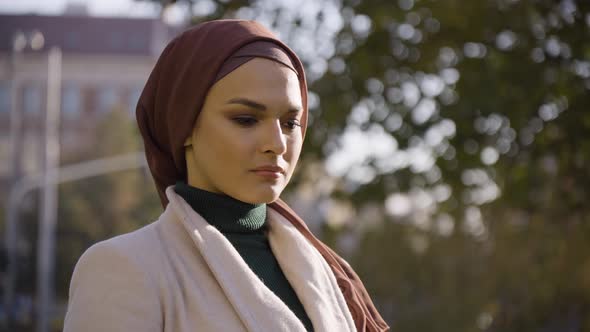 A Young Beautiful Muslim Woman Thinks About Something in a Park in an Urban Area  Closeup