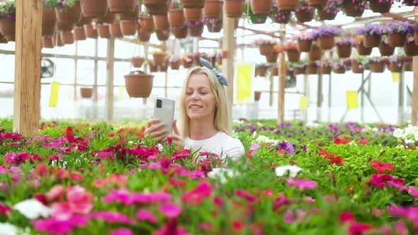 happy  Woman takes photos of colorful flowers on her phone and smiles.