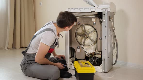 Master Opens Back Panel of Broken Washing Machine