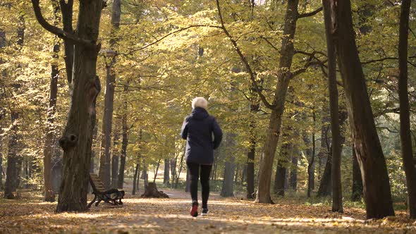 Sporty Aged Woman Running Along Park Alley