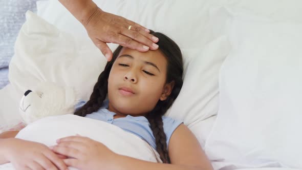 Grandmother comforting sick granddaughter in bed room 4k