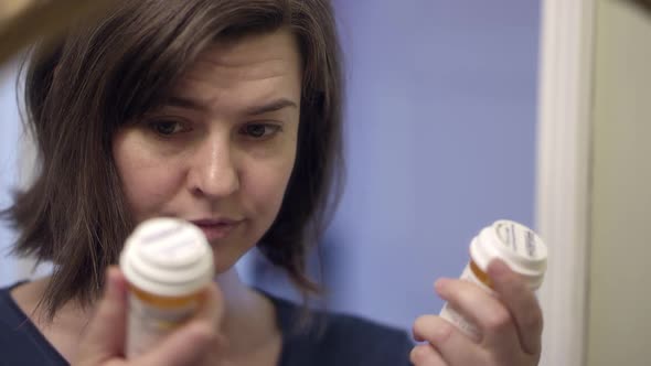 Depressed woman holding up two prescription bottles