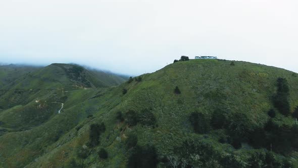 Drone camera approaching a large house on the top of a mountain range into the fog (California, USA)