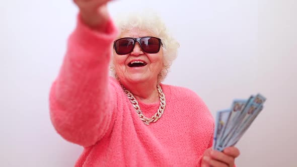 Blonde Old Lady Wear Pink Sweater and Sunglasses Showing Money Isolated White Background