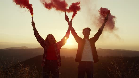 Woman and Man with Smoke Bombs Standing in Meadow