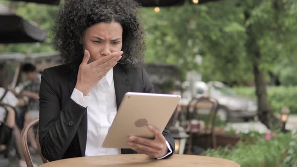 Shocked African Woman Upset by Loss on Tablet, Sitting in Outdoor Cafe