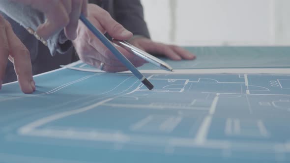 Architect and Engineer in a team discussing house blueprints, closeups pointing to a drawing