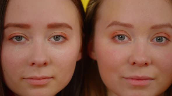 Closeup Faces of Identical Twin Sisters Looking at Camera