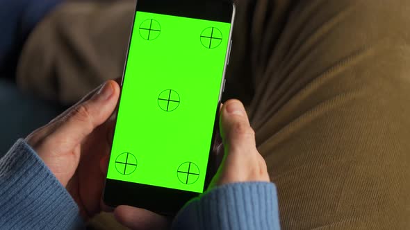 Man Using Smartphone with Green Mockup Screen in Vertical Mode