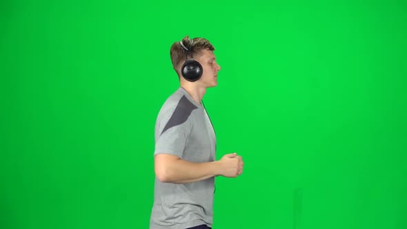 Handsome Guy in Big Headphones Is Running, Chroma Key. Side View. Slow Motion