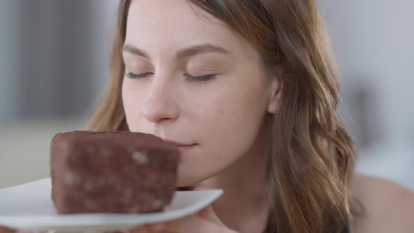 Closeup of Slim Caucasian Young Beautiful Woman Enjoying Smell of Chocolate Cake Licking Lips