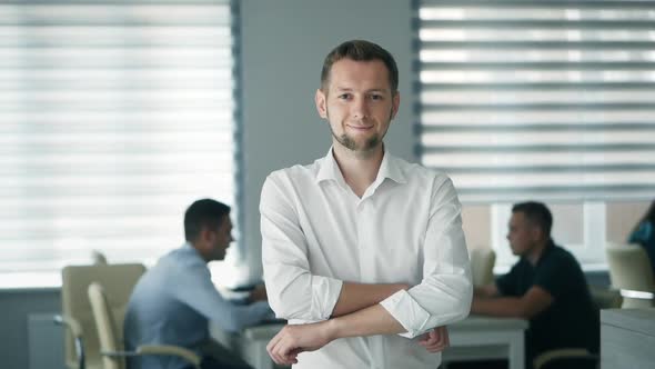 Successful Man in the Office in the Background Employees at Work Looking at the Camera