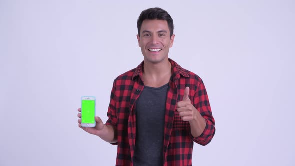 Happy Young Hispanic Hipster Man Showing Phone and Giving Thumbs Up