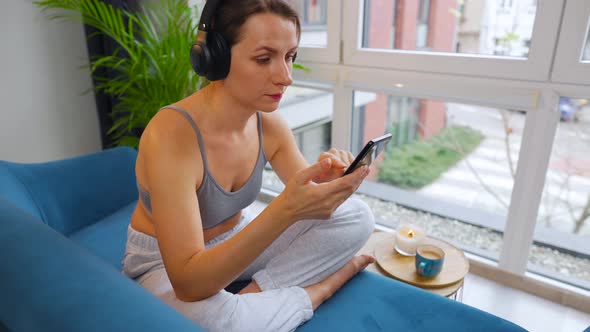 Woman in Wireless Headphones Listening to Music and Using Mobile Apps or Communicates on Social