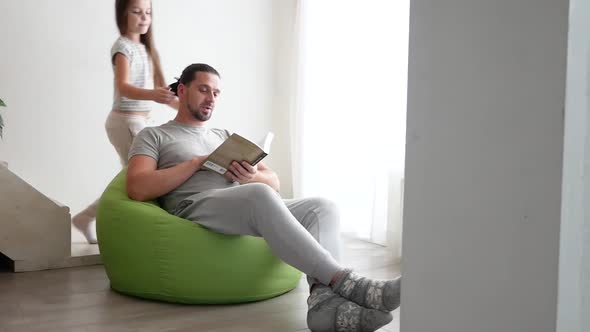 Teen Girl with Long Hair is Hugging Her Dad and Laughing in the Living Room at Home