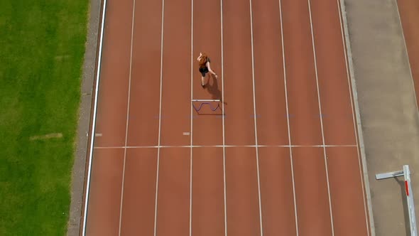 Female athletic jumping over hurdle on sports track 4k