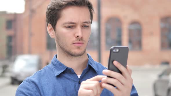 Outdoor Portrait of Young Man Using Smartphone